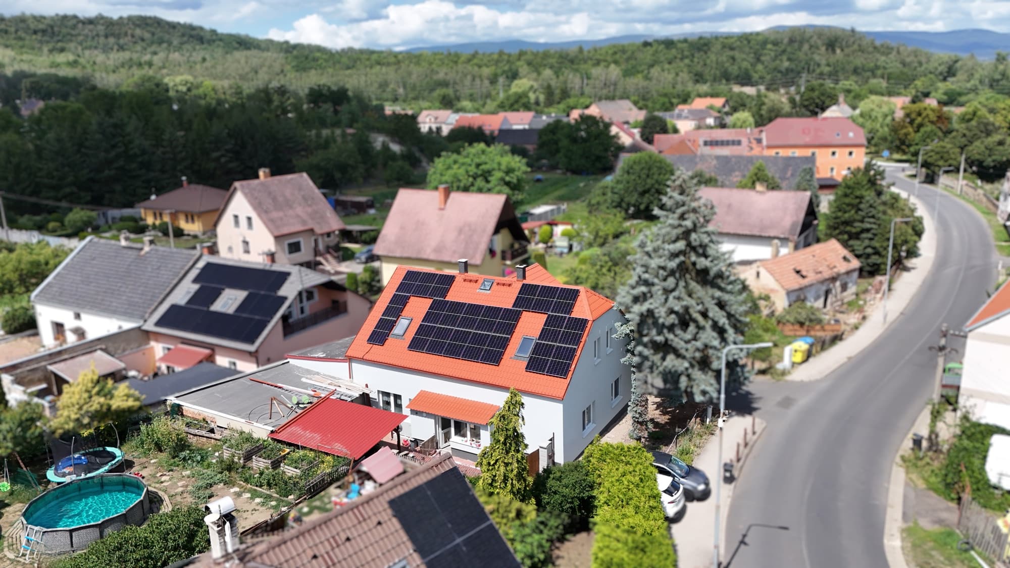 Rodinný dům s fotovoltaikou v Braňanech — letecký pohled na obec a kopce